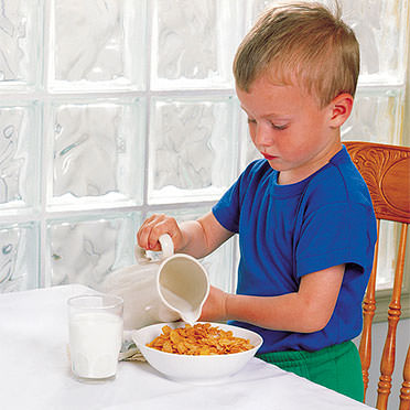 Child pouring milk on cereal